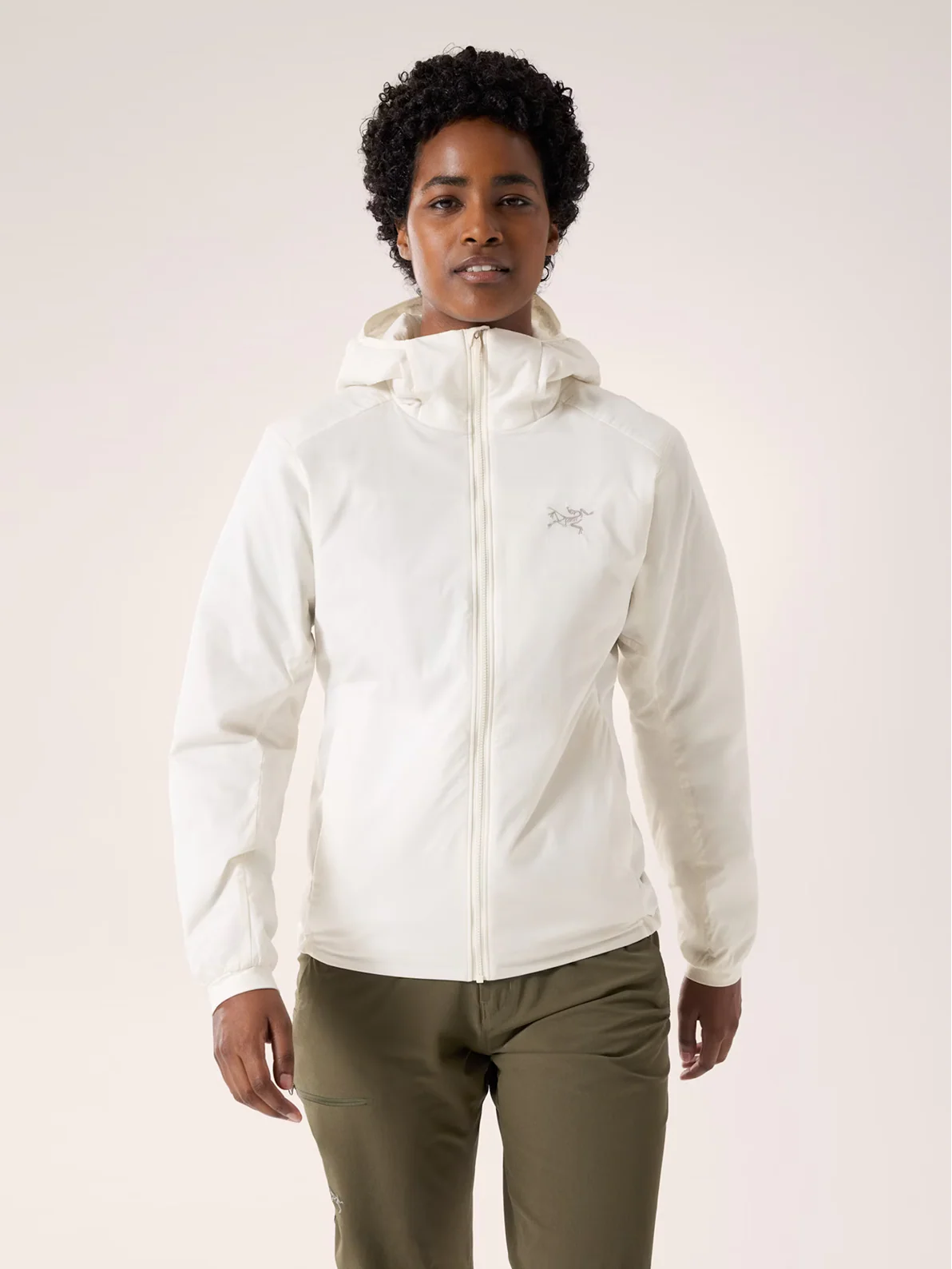 A woman wearing a white hooded jacket and olive green pants.