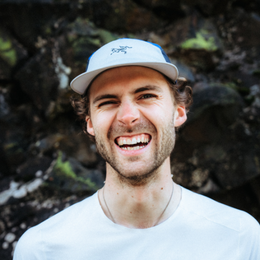 a man wearing a hat and a white shirt is smiling