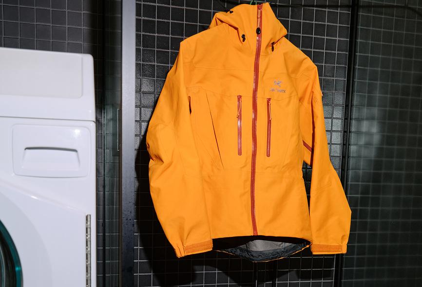 Orange Arc'teryx jacket hanging next to a washing machine.