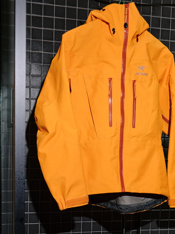 Orange Arc'teryx jacket hanging next to a washing machine.
