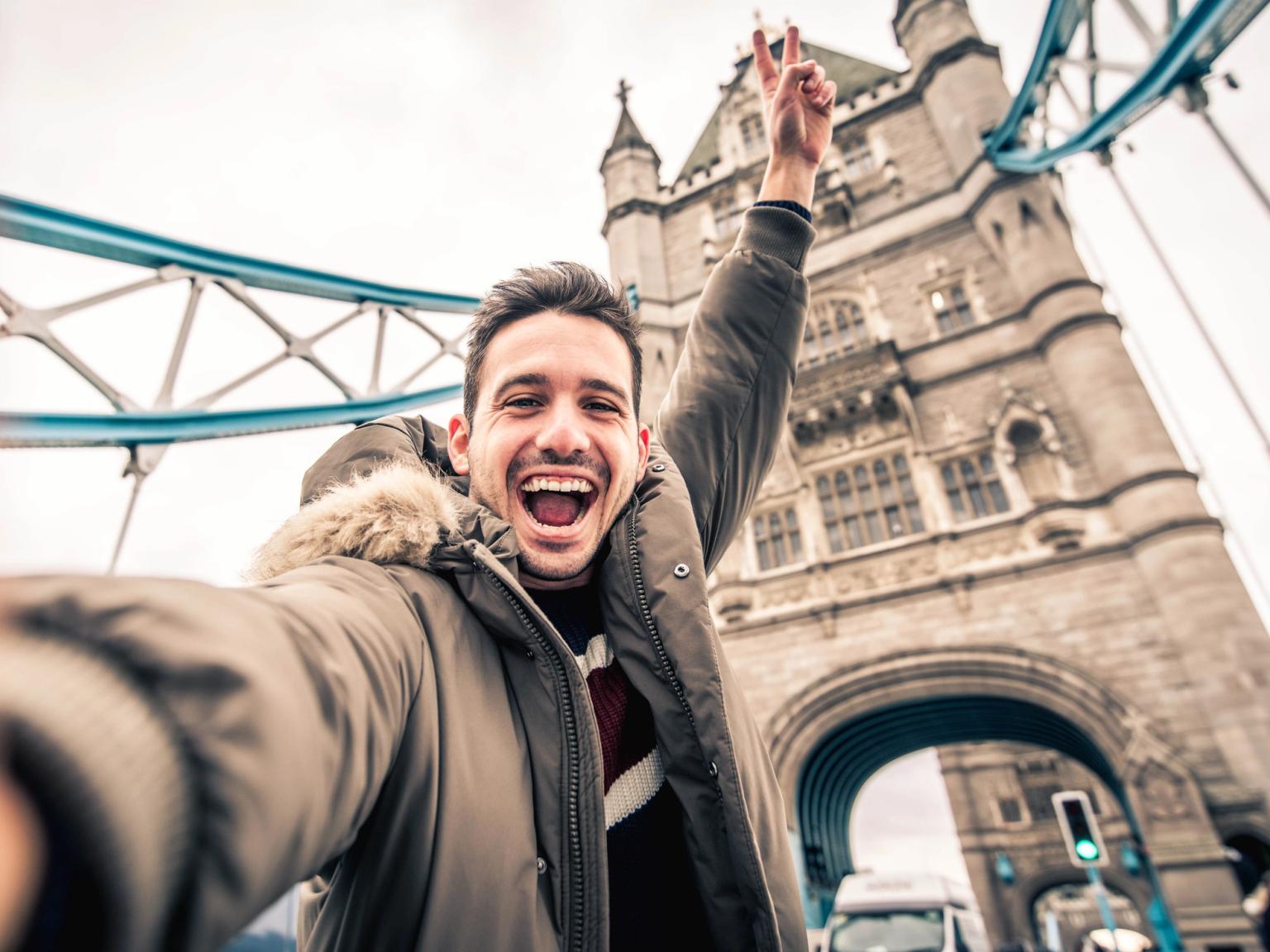 en man tar en selfie framför tower bridge i london