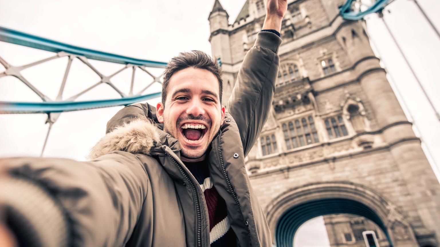en man tar en selfie framför tower bridge i london