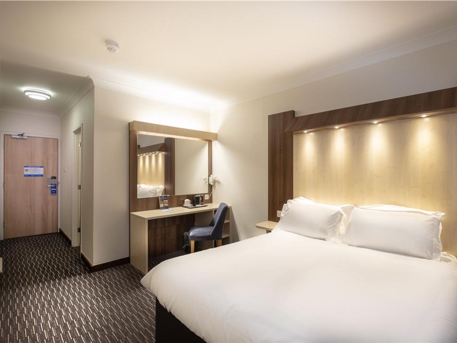 et hotellrom med en king size seng, skrivebord, stol og speil
