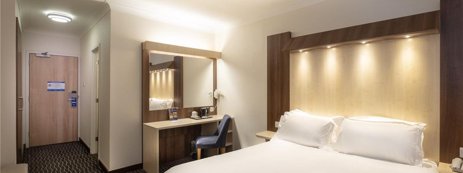 et hotellrom med en king size seng, skrivebord, stol og speil