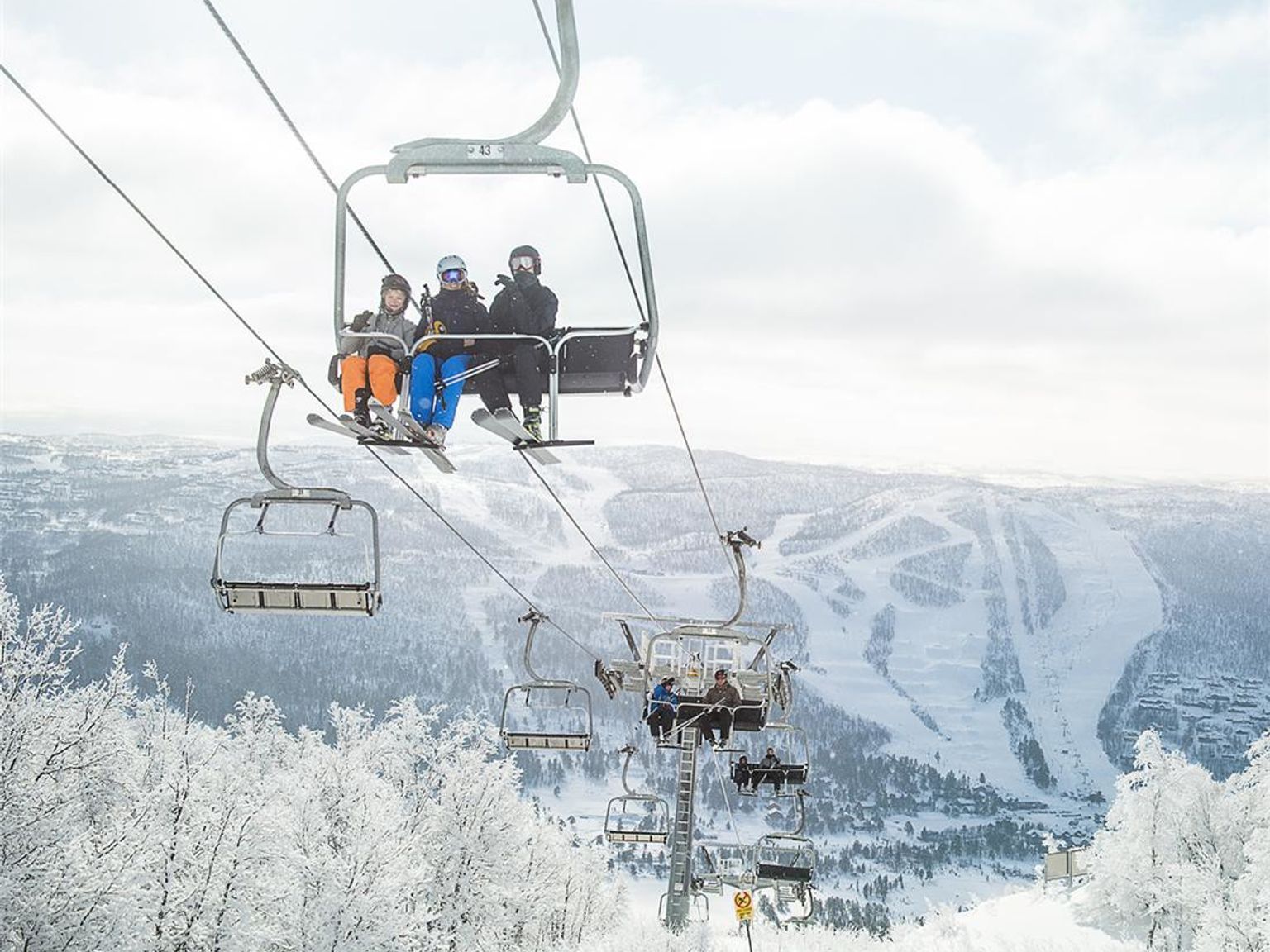 en gruppe mennesker kjører skiheis opp en snødekket fjell.