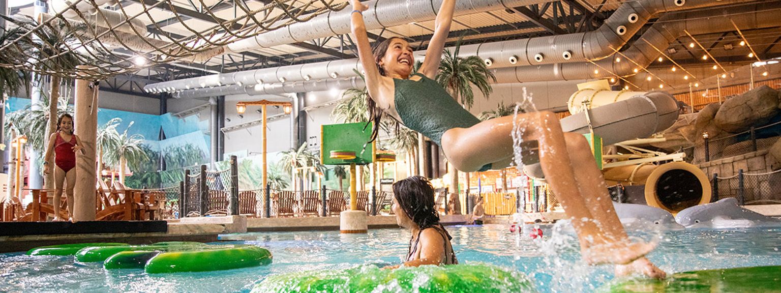 en pige løftes i luften, mens hun rider på et rør i en vandpark