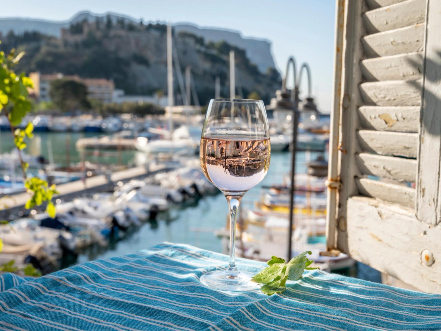 et glas vin sidder på et bord foran et vindue med udsigt over en havn