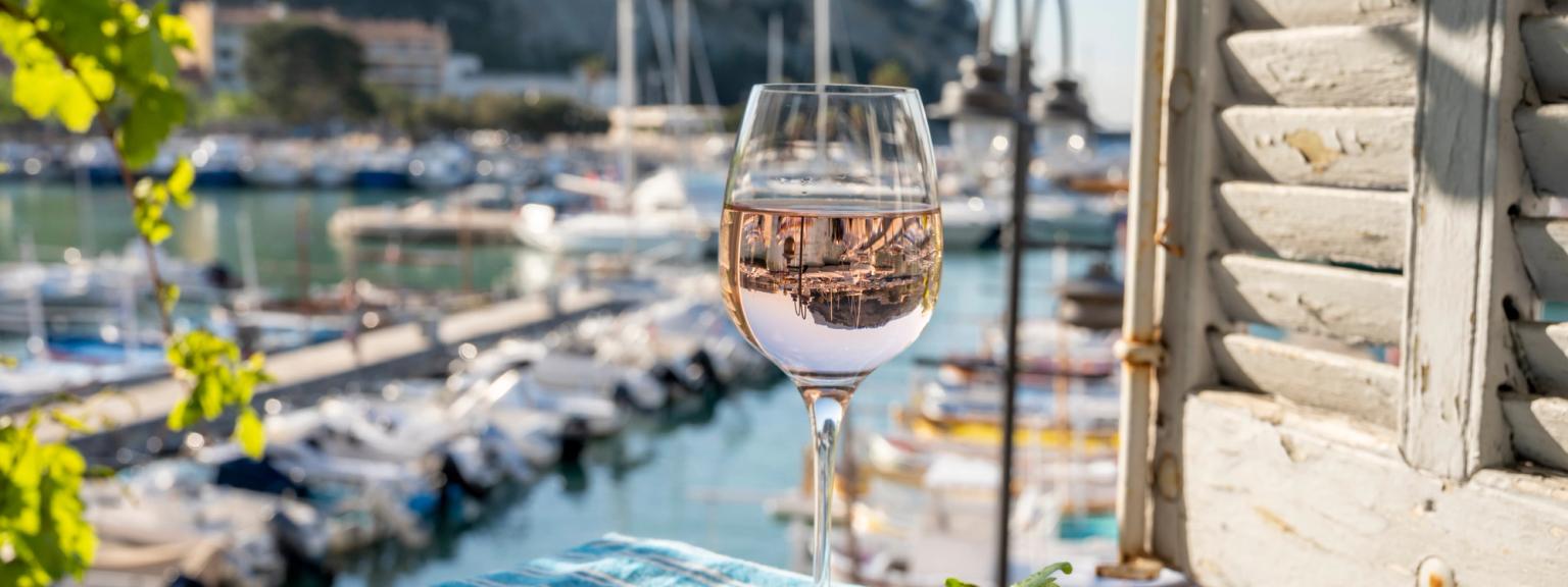 et glas vin sidder på et bord foran et vindue med udsigt over en havn