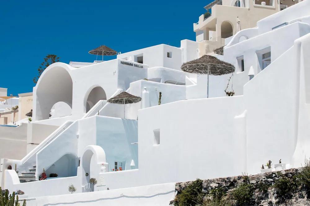 en hvit bygning med trapper og paraplyer på toppen av den