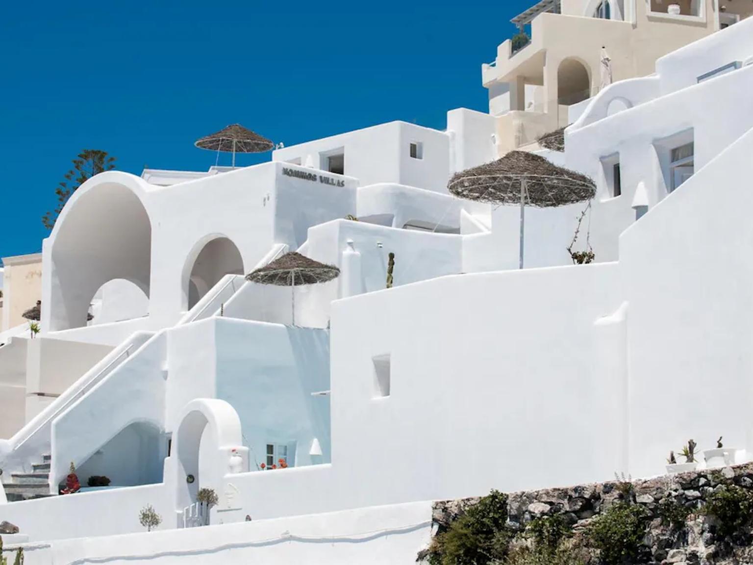 en hvit bygning med trapper og paraplyer på toppen av den