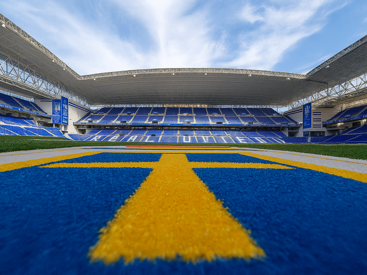 Leeres modernes Stadion mit blauen Sitzen, einem grünen Spielfeld und einer blauen Laufbahn mit gelben Markierungen.