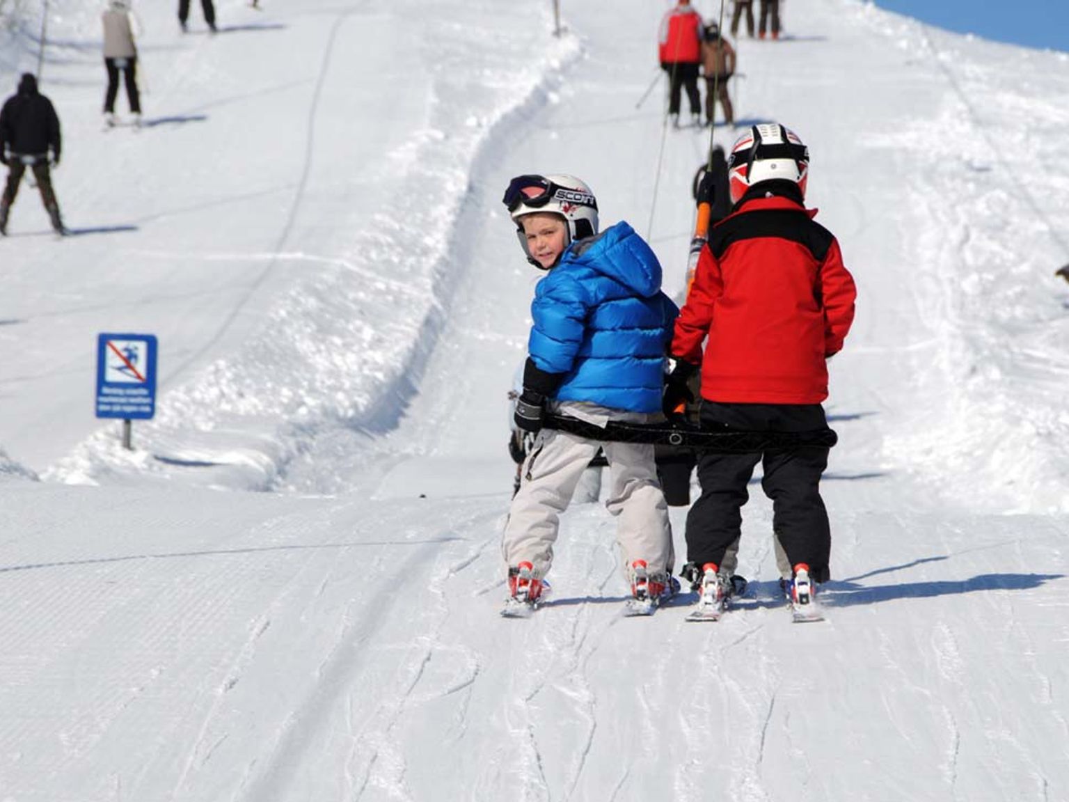 en gruppe barn skier ned en snødekket skråning