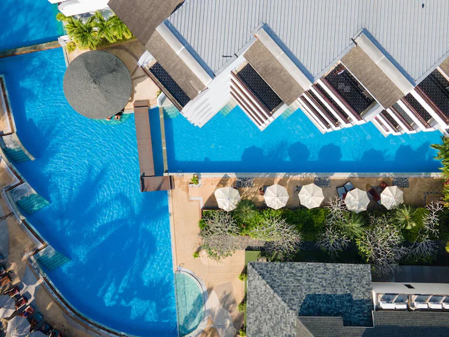 et luftfoto af en stor swimmingpool omgivet af stole og parasoller