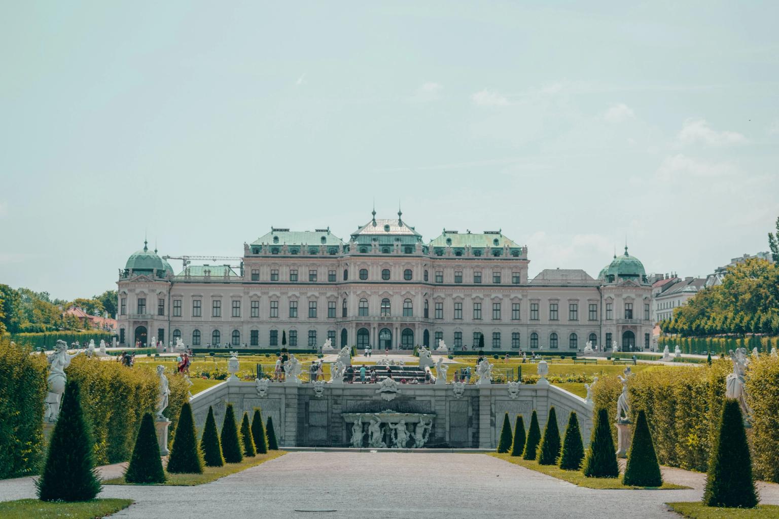 Belvederepalatset i Wien, en stor byggnad med en fontän framför, omgiven av träd och statyer.
