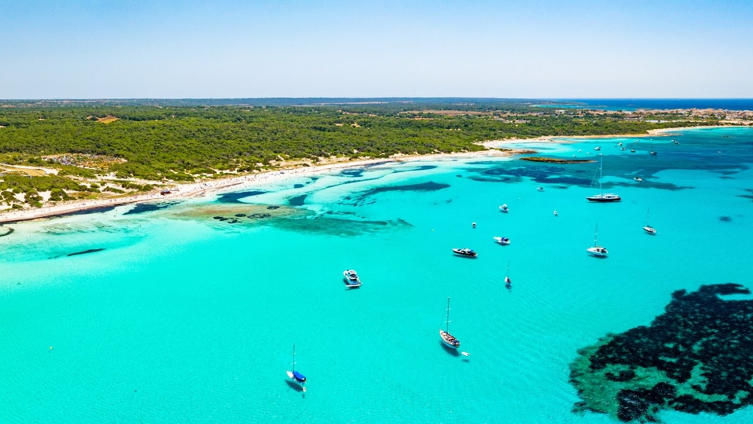 Luftfoto av en tropisk bukt med turkis vann, en sandstrand og flere båter. Es Trenc, Mallorca