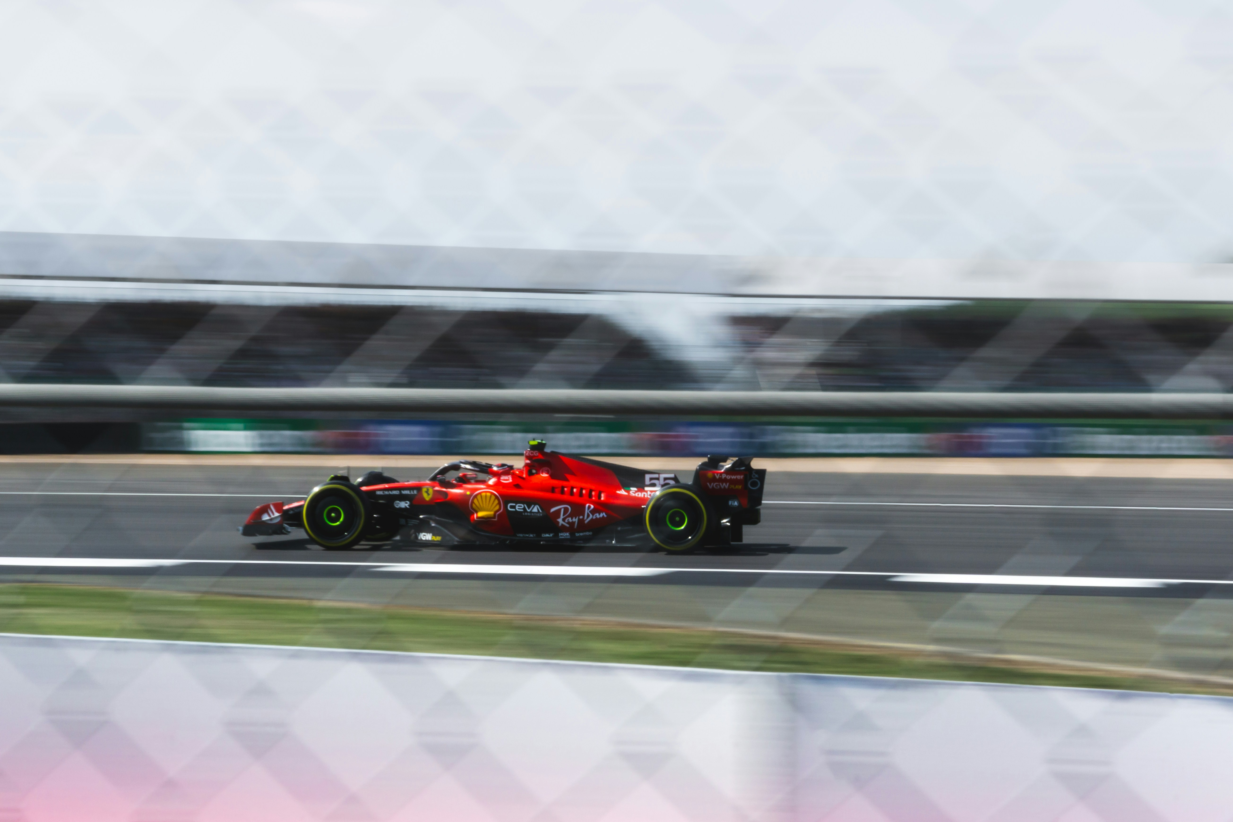 A red Formula 1 car speeds on a racetrack with motion blur.