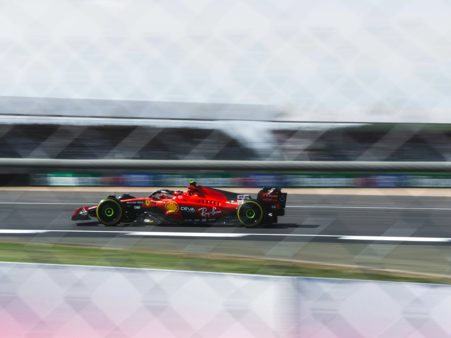 A red Formula 1 car speeds on a racetrack with motion blur.