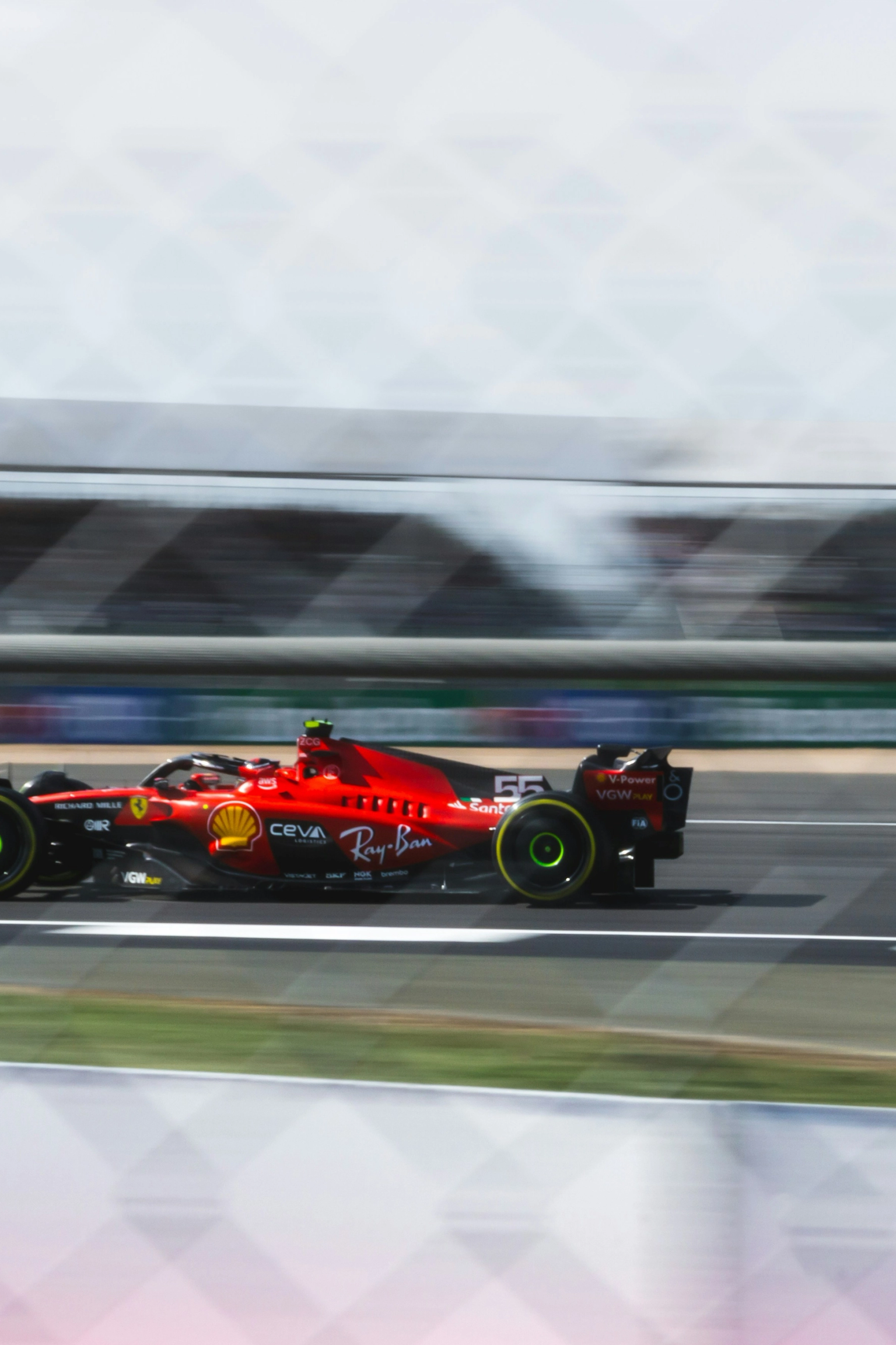 A red Formula 1 car speeds on a racetrack with motion blur.