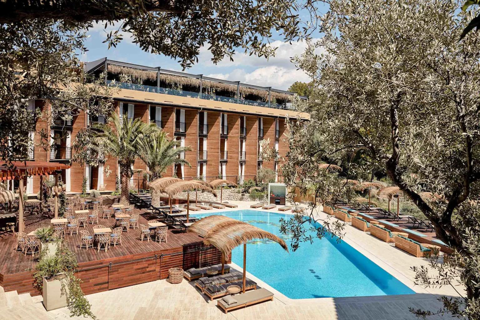 Ett modernt hotell med träfasader, en utomhusmatsal, en stor swimmingpool och solstolar med halmparasoller, omgiven av träd. Bikini Island & Mountain Hotel Port de Sóller - Endast för vuxna