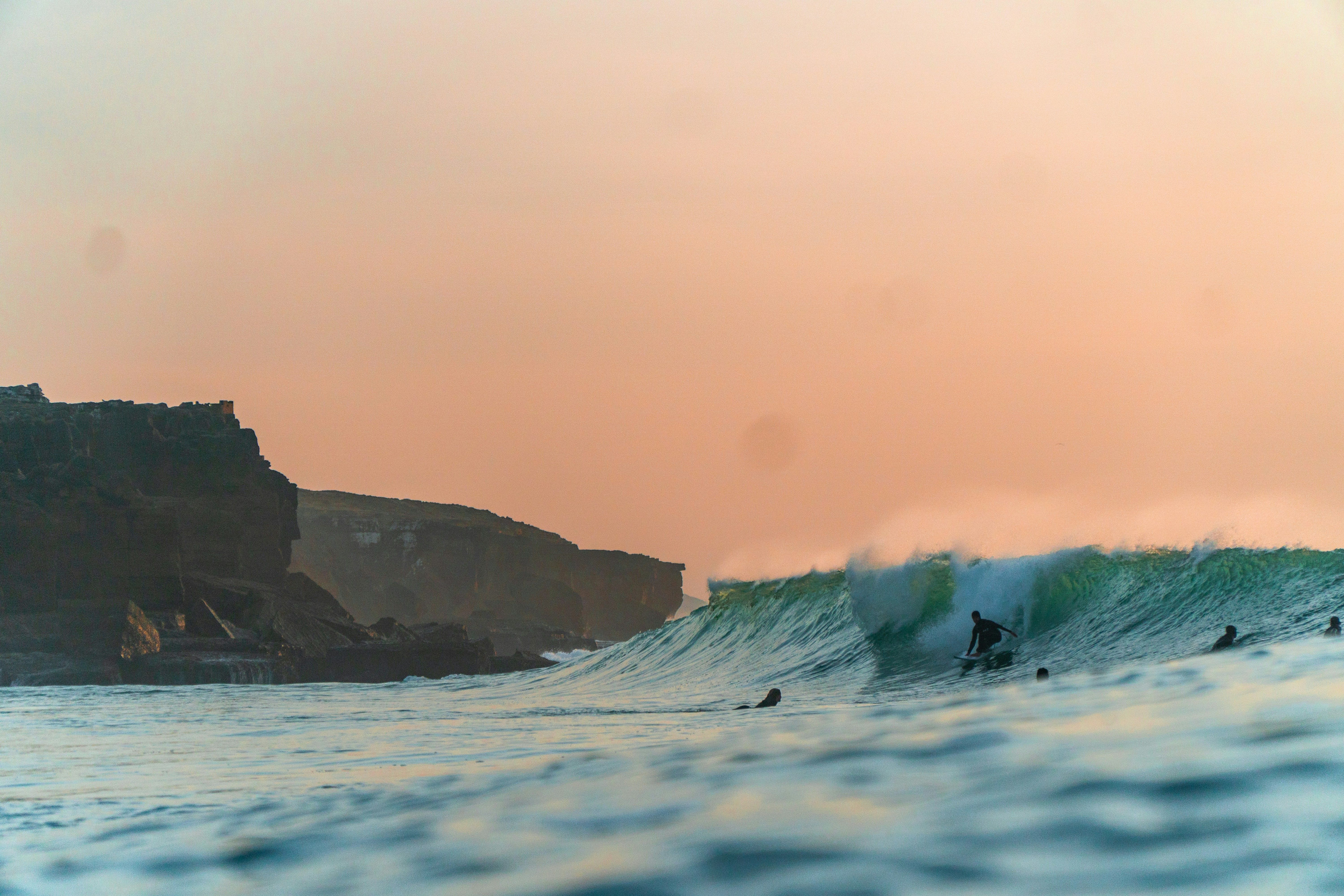 a group of surfers are riding a wave in the ocean at sunset.