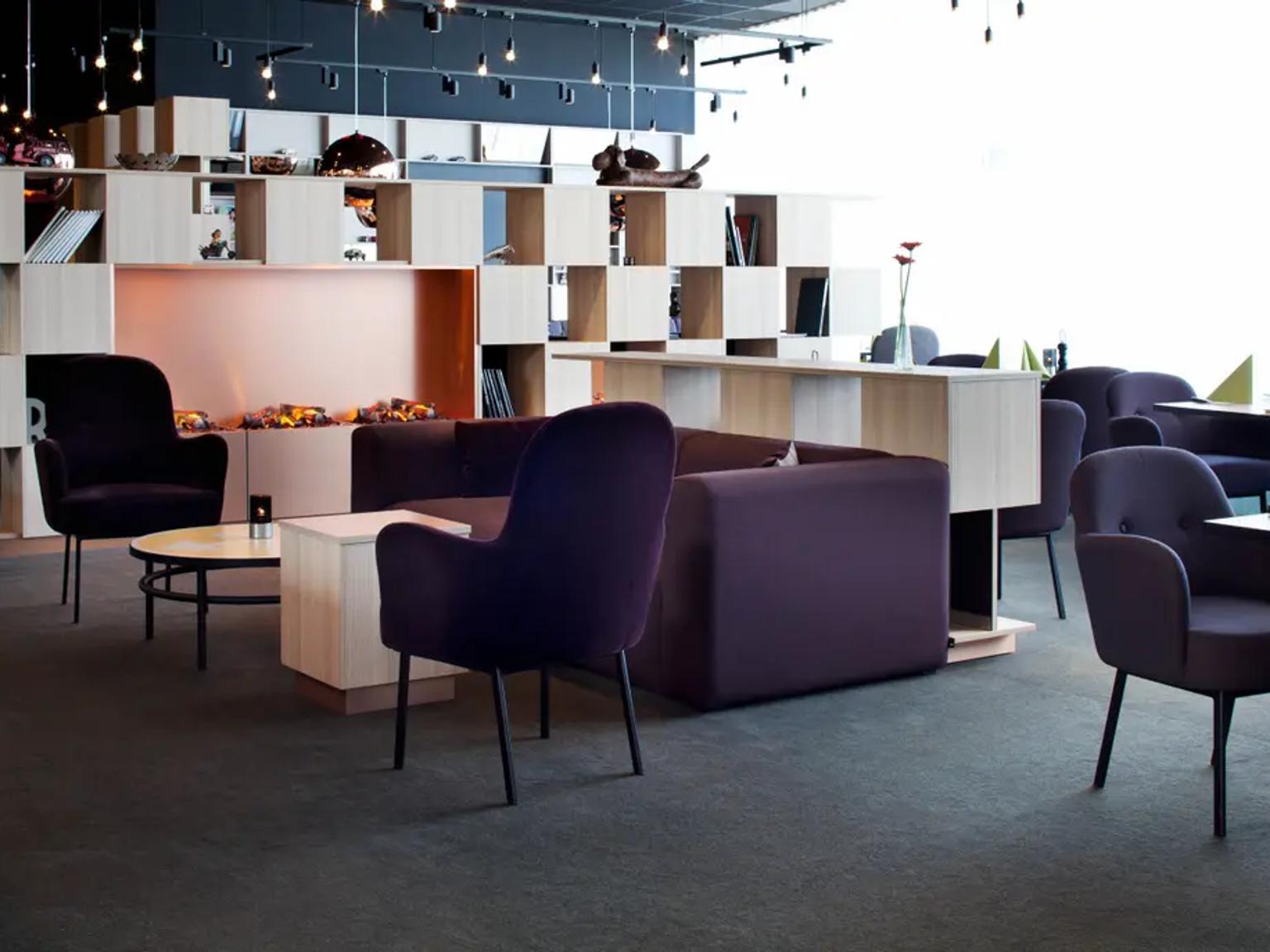 Moderne lounge og spiseområde med lilla sitteplasser, en lys tre modulær skillevegg og lyse vinduer. Scandic Kolding