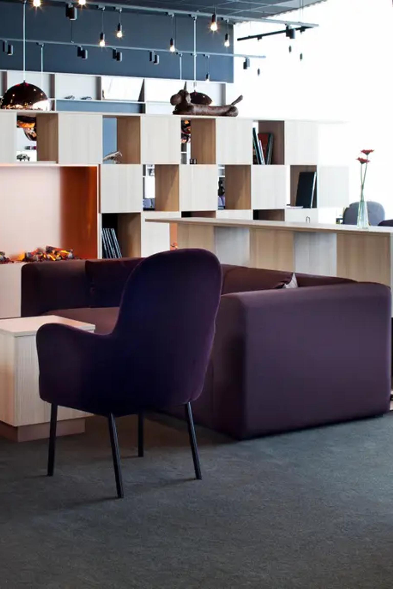 Moderne lounge og spiseområde med lilla sitteplasser, en lys tre modulær skillevegg og lyse vinduer. Scandic Kolding