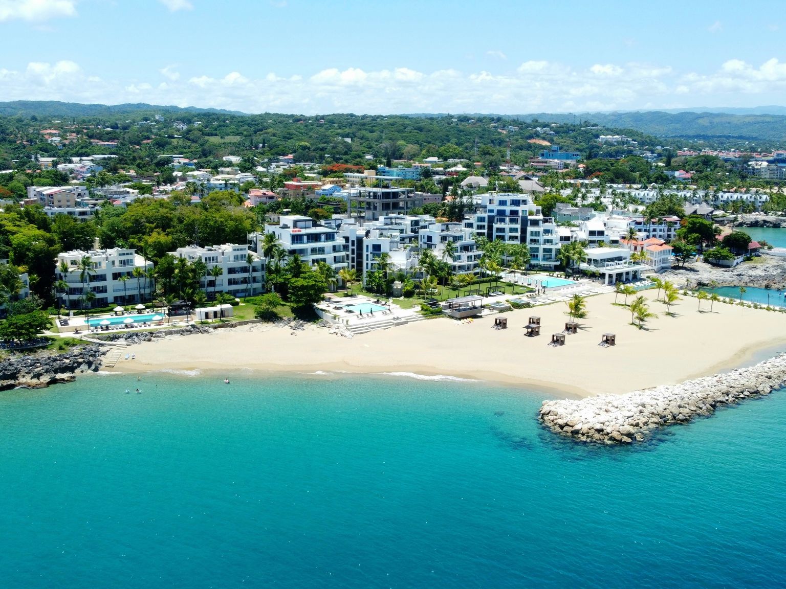en flygvy över en strand med många byggnader och paraplyer