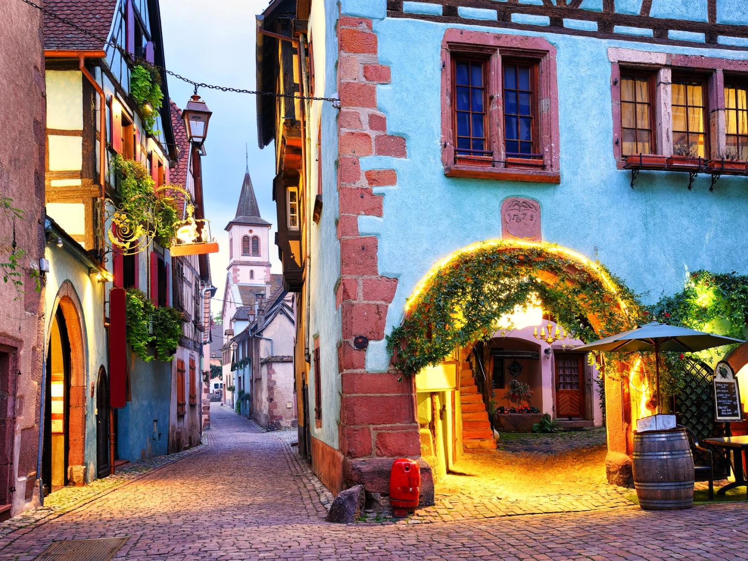 en smal brosteinsgate i en liten by med en kirke i bakgrunnen