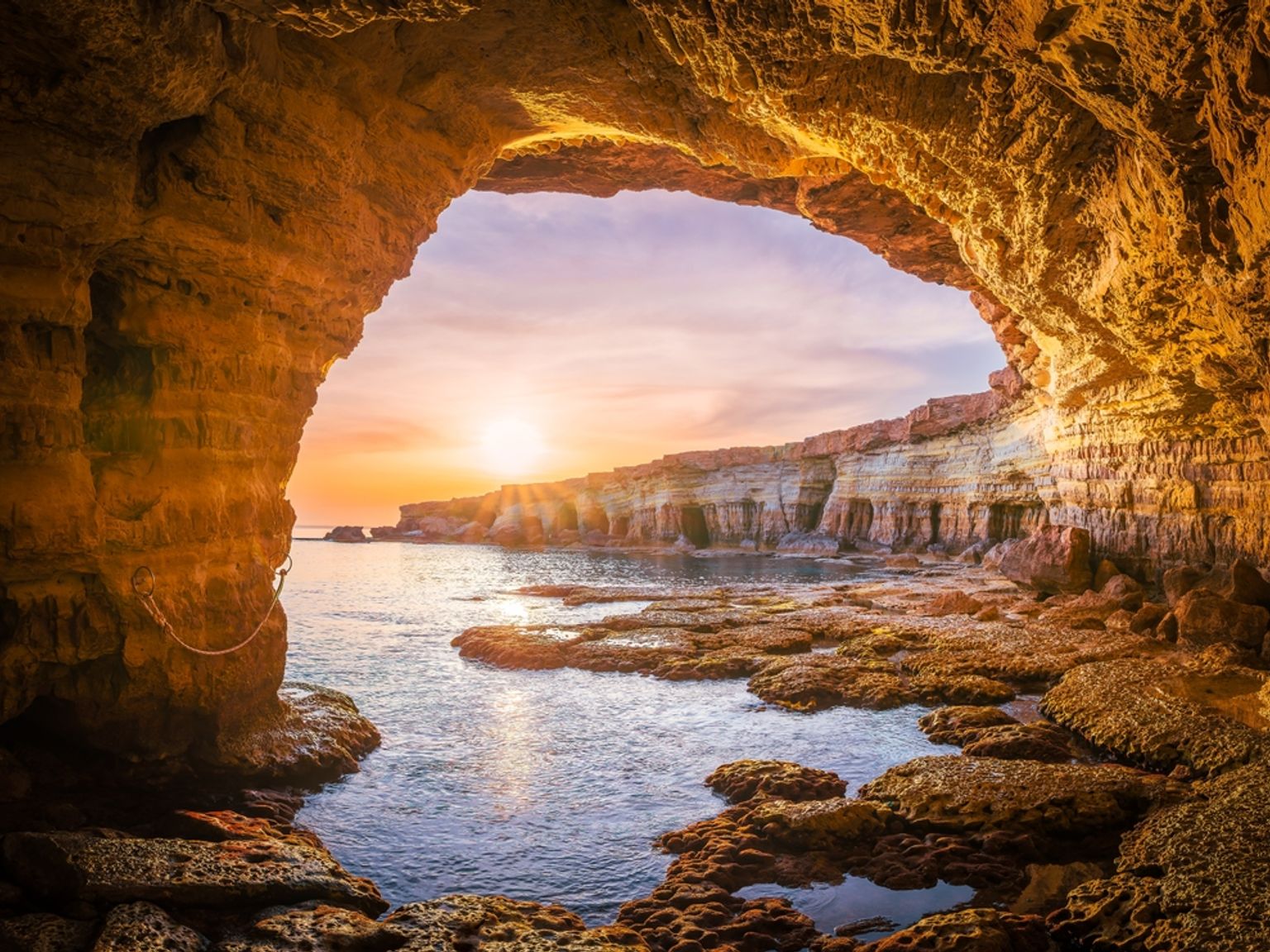 en vy över havet från insidan av en grotta vid solnedgången