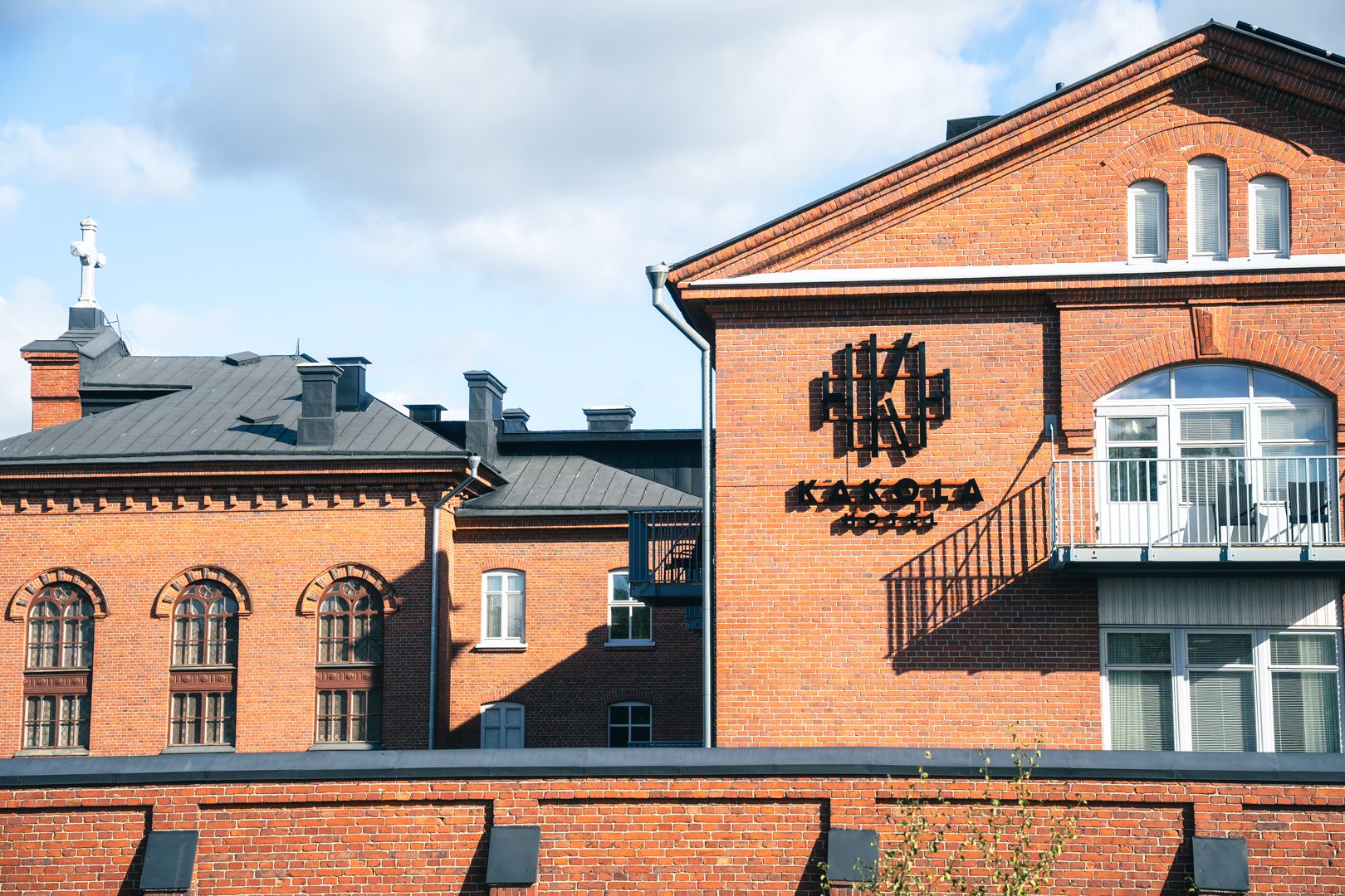 Punatiilisiä rakennuksia, joista yhdessä on kattoristi ja toisessa "KAKOLA"-kyltti ja parveke.