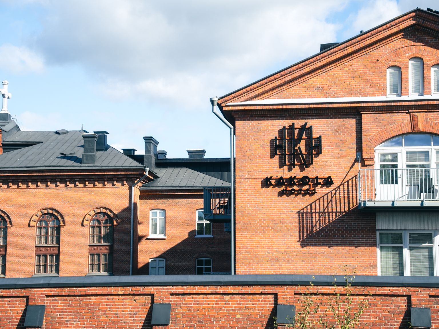 Punatiilisiä rakennuksia, joista yhdessä on kattoristi ja toisessa "KAKOLA"-kyltti ja parveke.