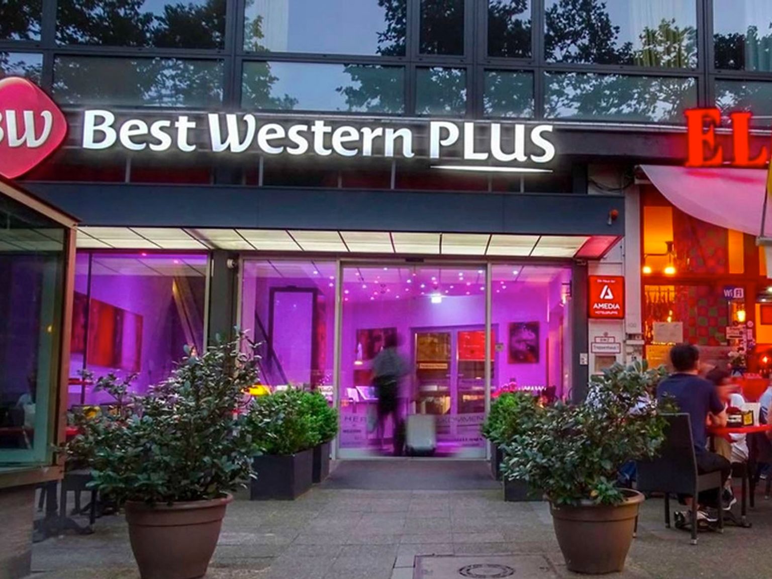 en grupp människor sitter utanför ett best western plus hotell