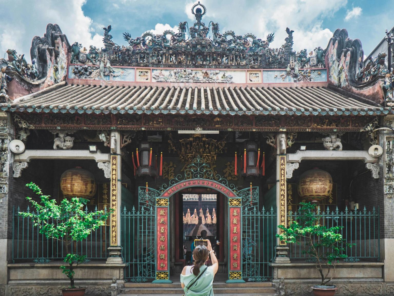 En person fotograferer et udsmykket, farverigt tempel med et tegltag. Ho Chi Minh City