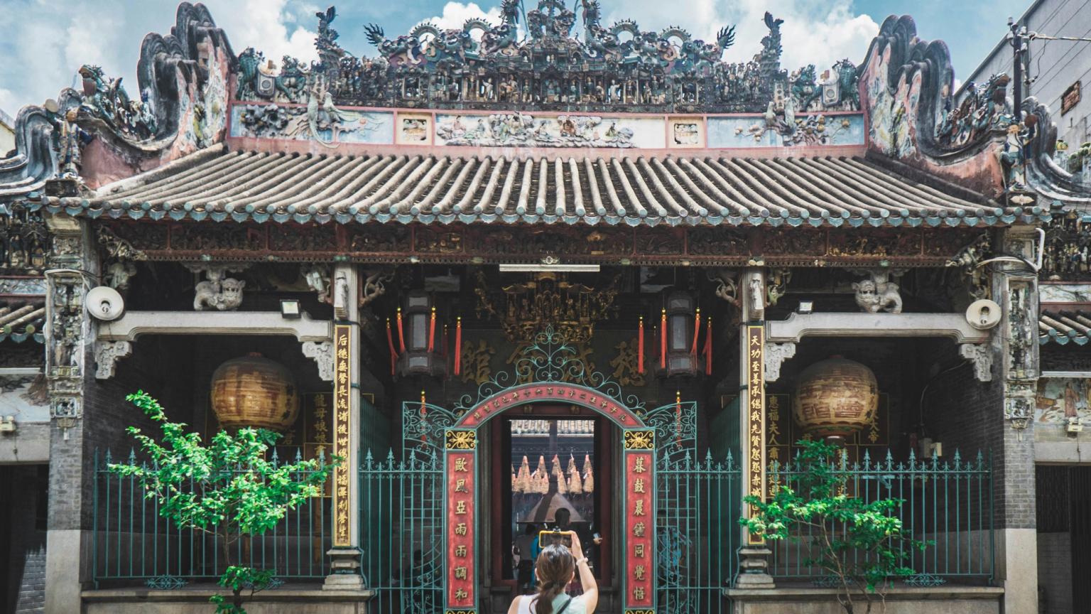 En person fotograferer et udsmykket, farverigt tempel med et tegltag. Ho Chi Minh City