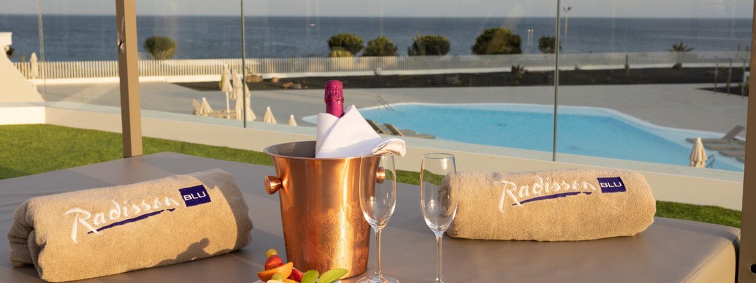 det er en bøtte med champagne og to glass vin på sengen