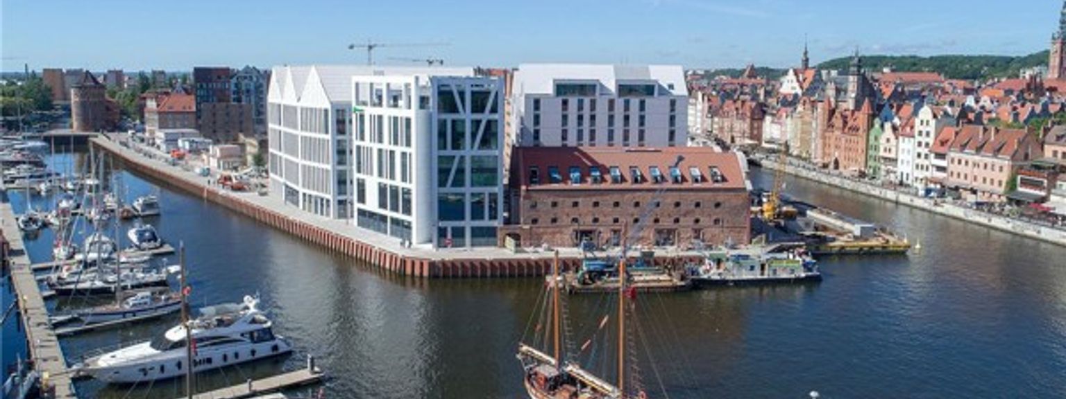 en flygvy över en hamn med båtar dockade och en stor byggnad i bakgrunden