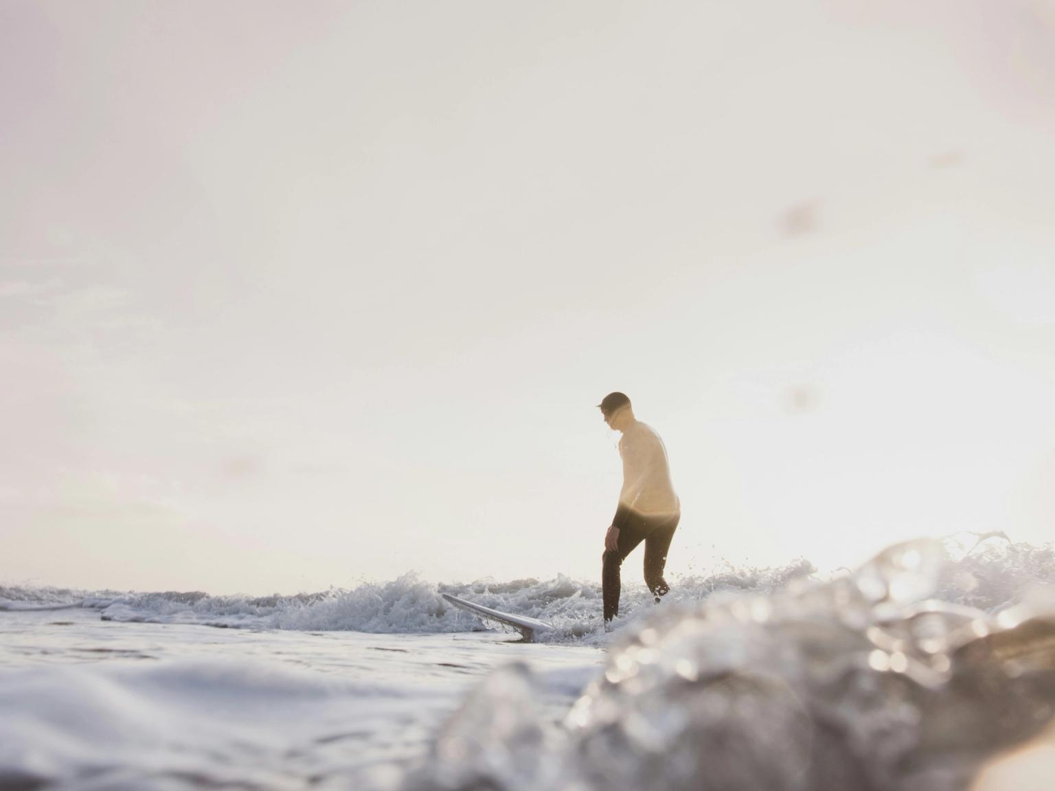 en man rider på en våg på en surfbräda i havet.
