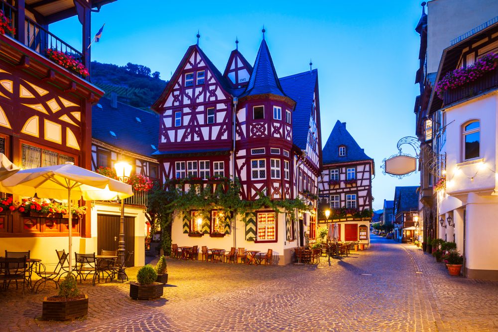 a cobblestone street with tables and chairs in a small town at night