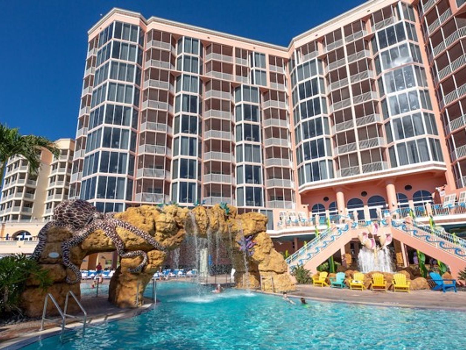 ett stort hotell med en pool och ett vattenfall framför det.
