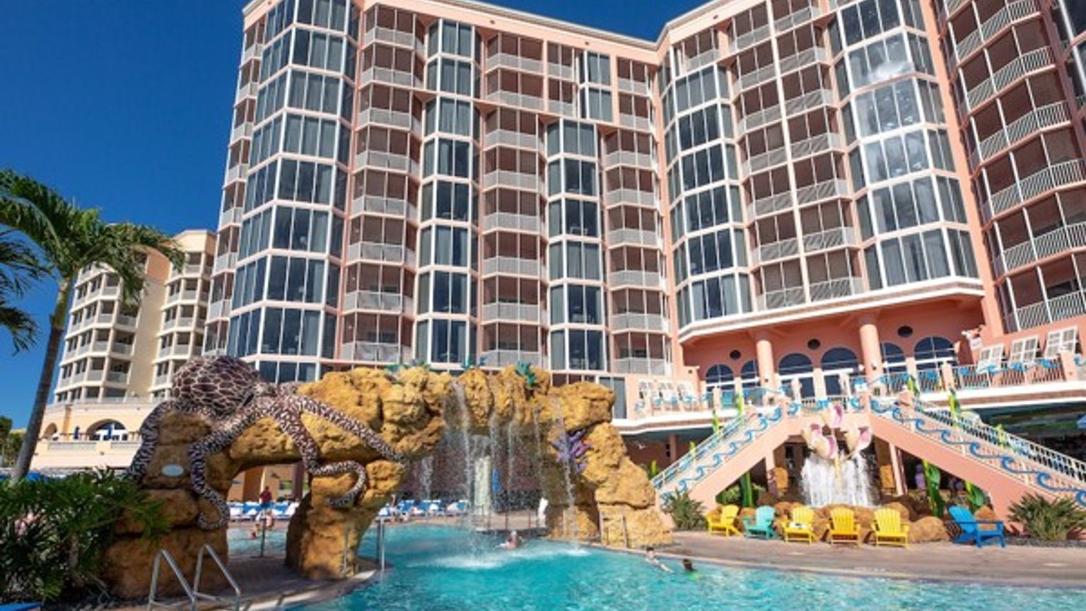 et stort hotell med et svømmebasseng og et fossefall foran det.