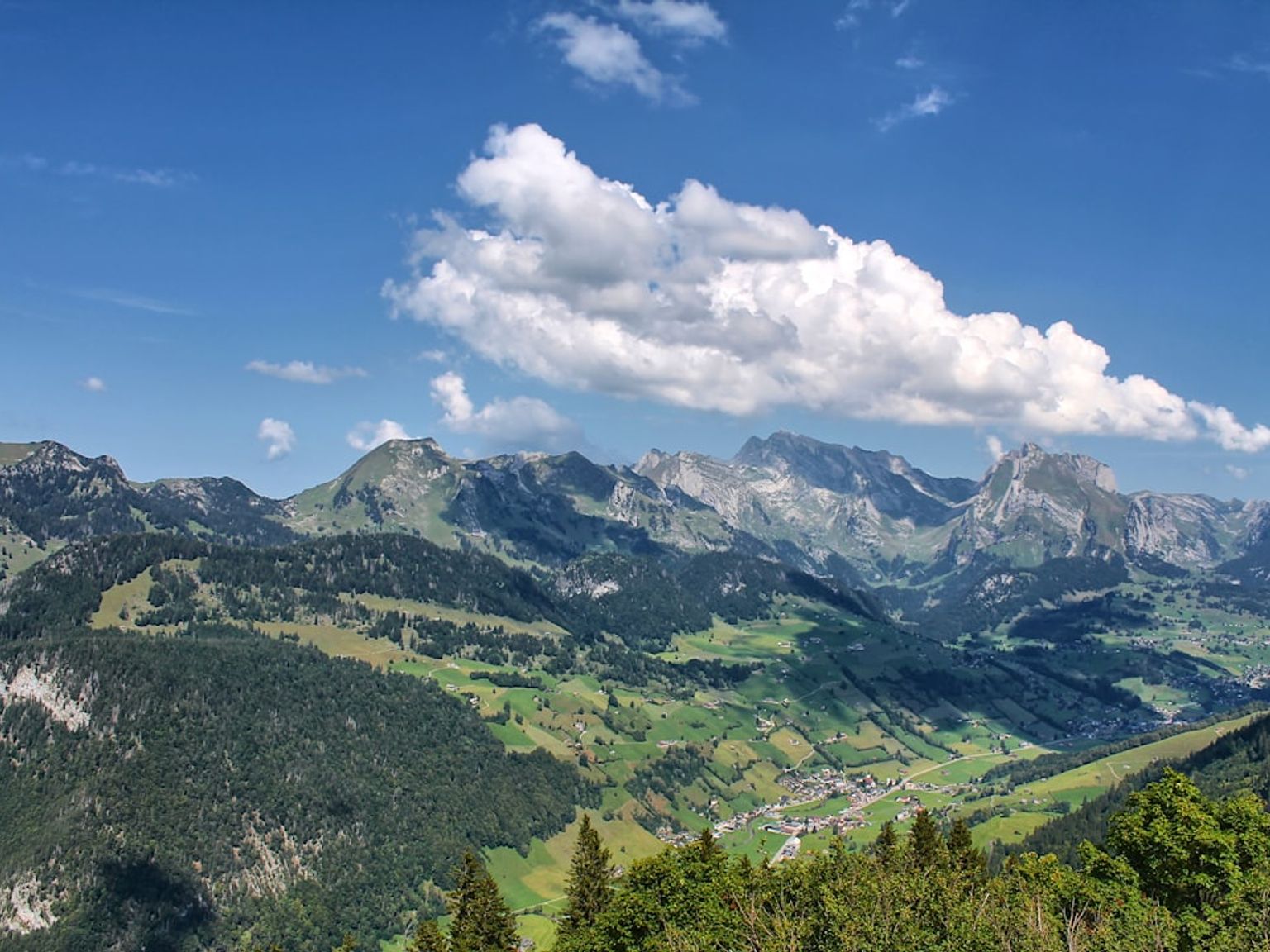 en vy över en bergskedja med ett moln på himlen