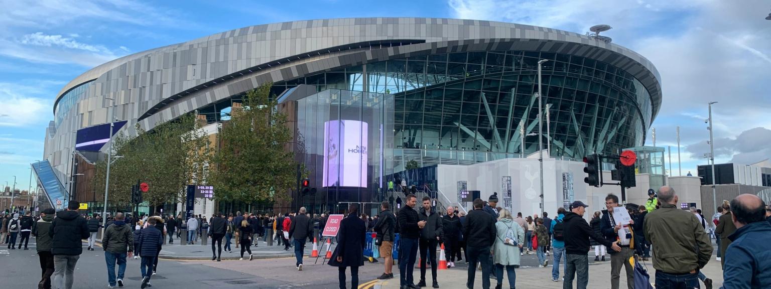 en grupp människor går nerför en gata framför en arena