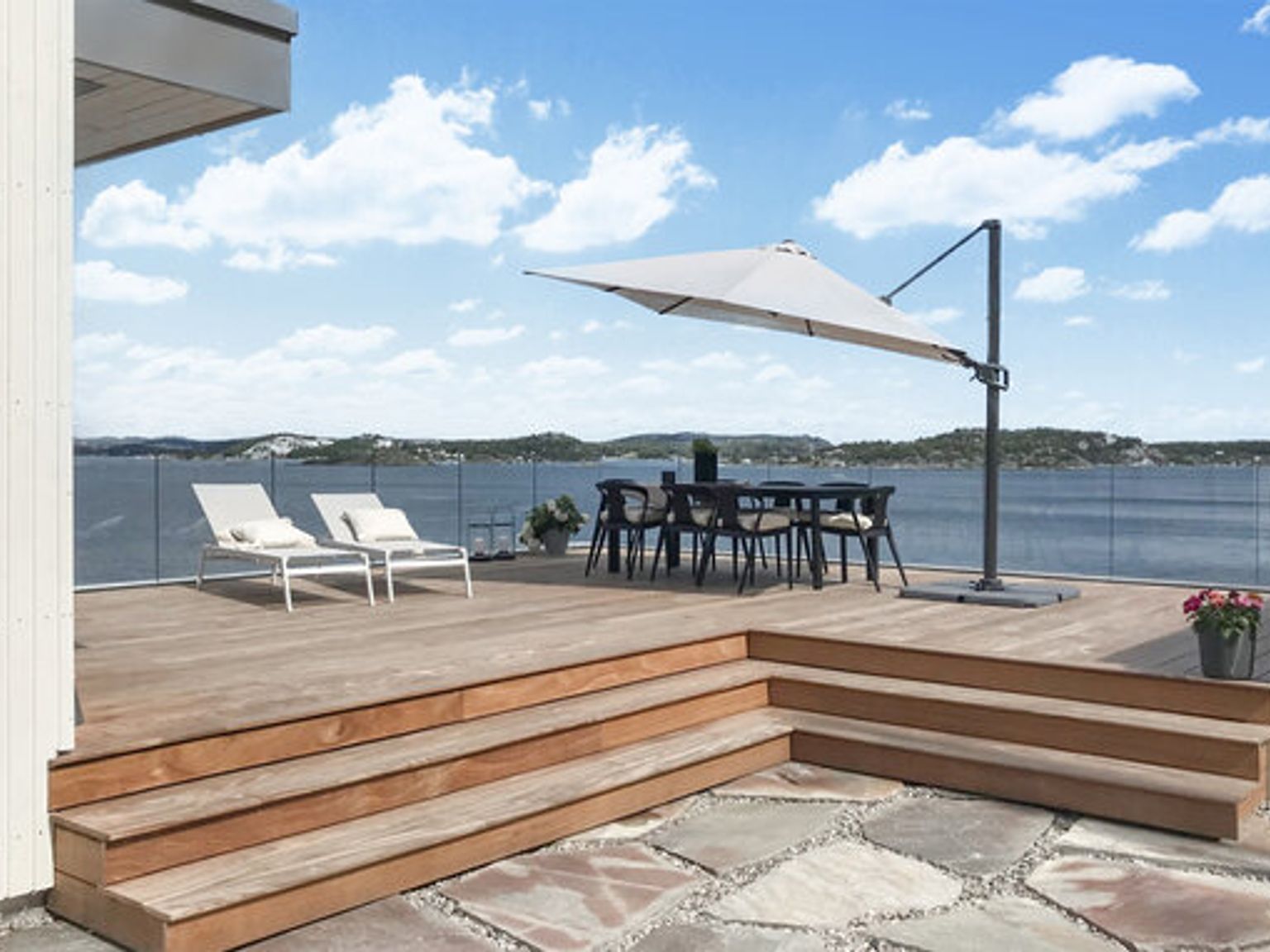 a wooden deck with a table and chairs and an umbrella overlooking the ocean
