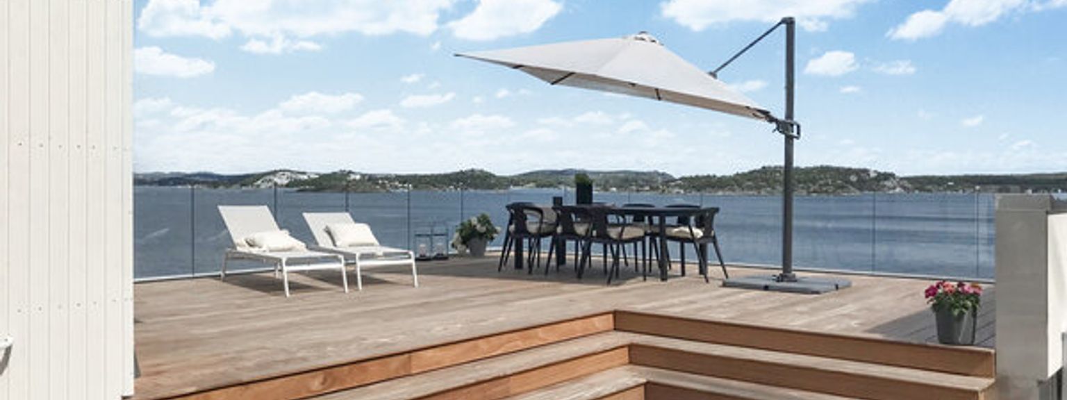 a wooden deck with a table and chairs and an umbrella overlooking the ocean