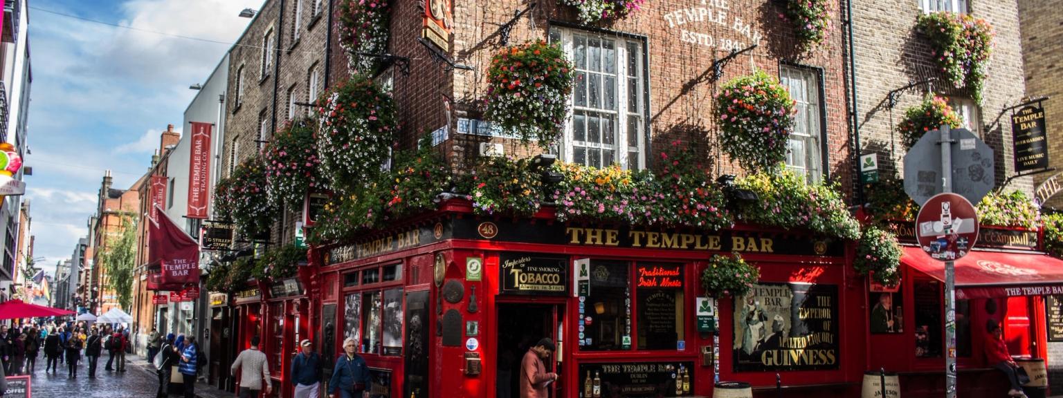 en grupp människor går nerför en kullerstensgata framför en röd byggnad, Dublin