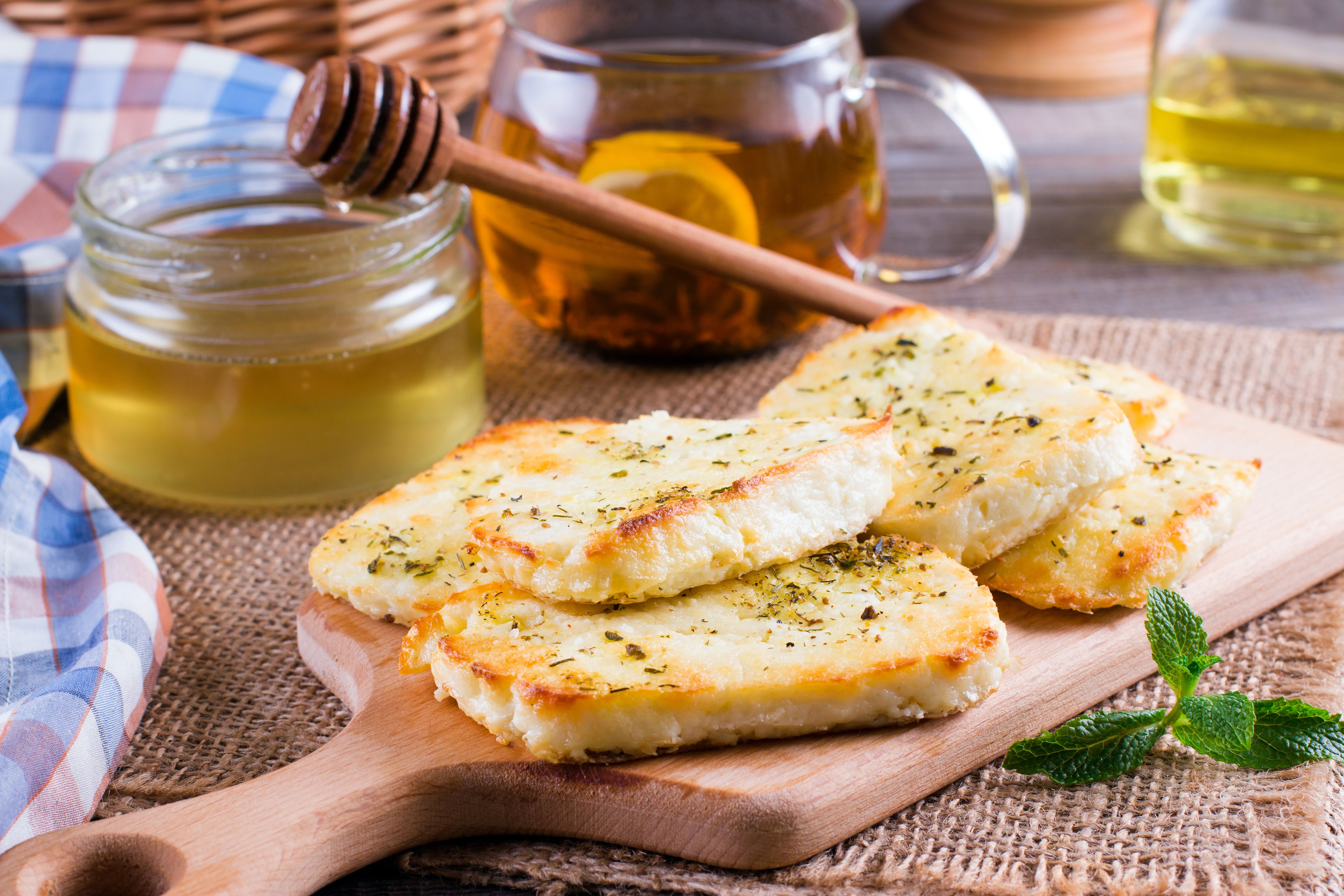 a wooden cutting board topped with slices of cheese and honey