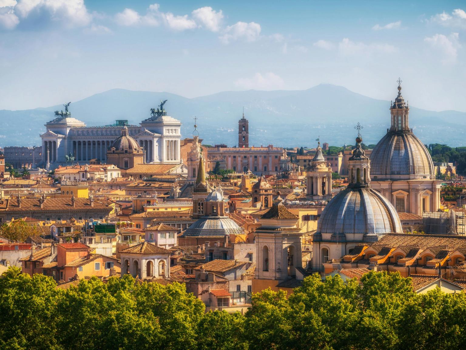 Panoramiczny widok na Rzym z historycznymi kopułami, pomnikiem Wiktora Emanuela II i górami w oddali. Rzym, Włochy