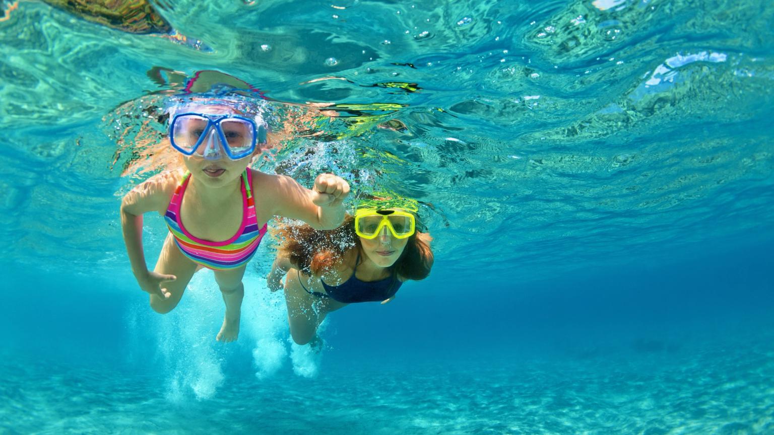 to unge jenter svømmer under vannet i havet