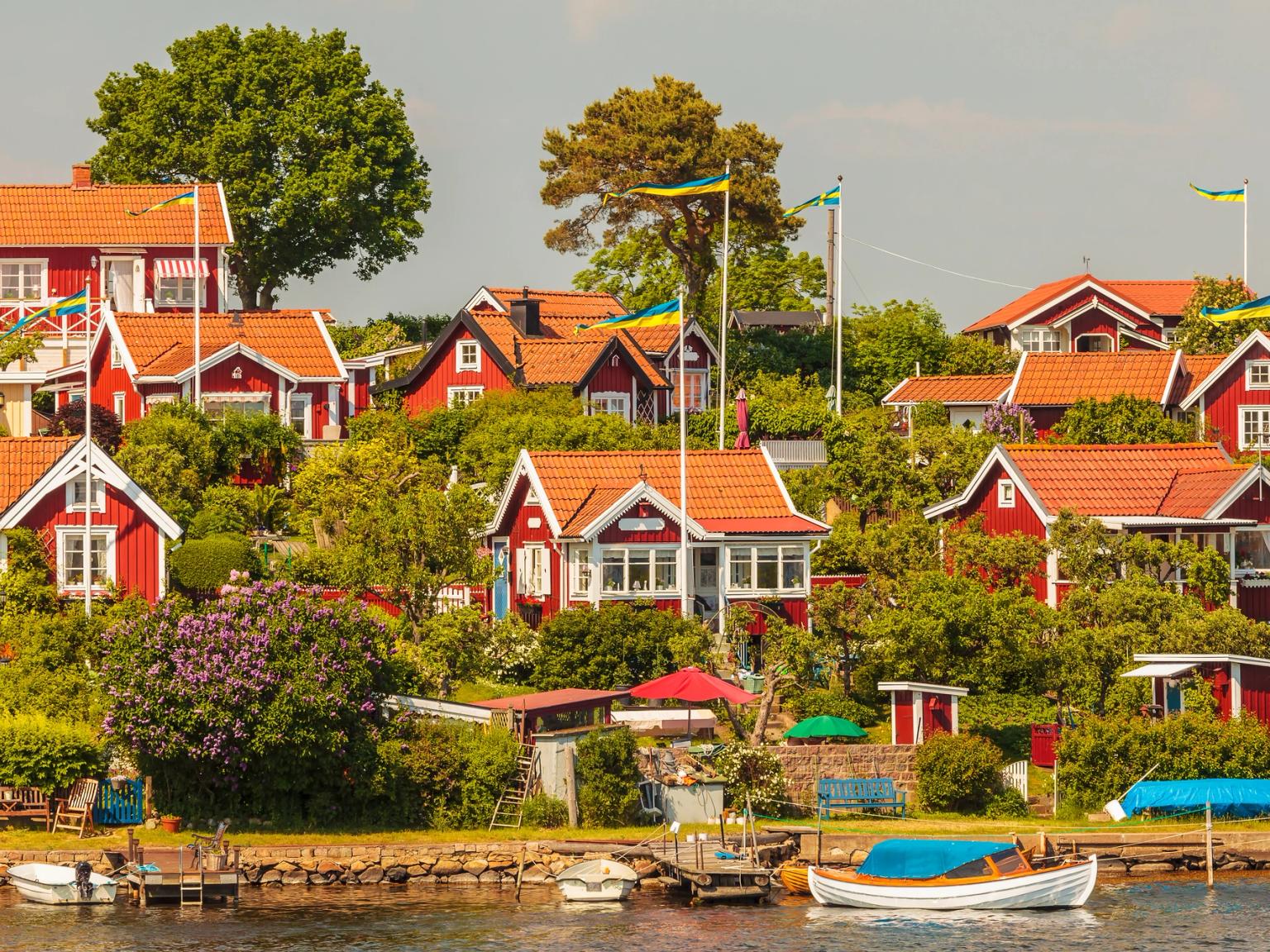 eine Gruppe roter Häuser, die auf einem Hügel neben einem Gewässer sitzen