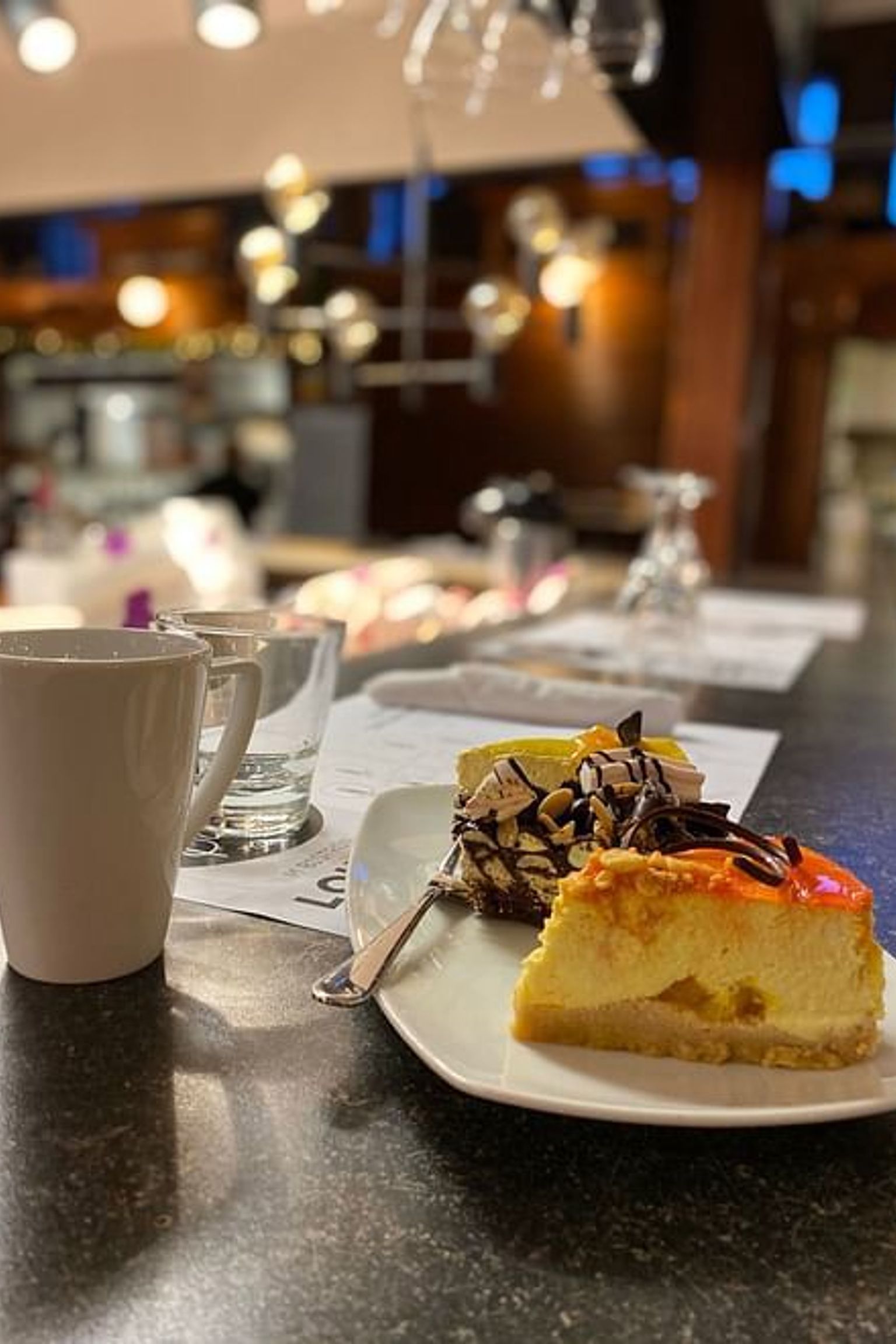a slice of cheesecake is on a plate next to a cup of coffee